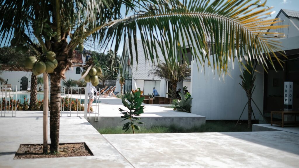 pexels-photo-19977307-19977307 A stylish tropical resort featuring palm trees, white buildings, and a pool.