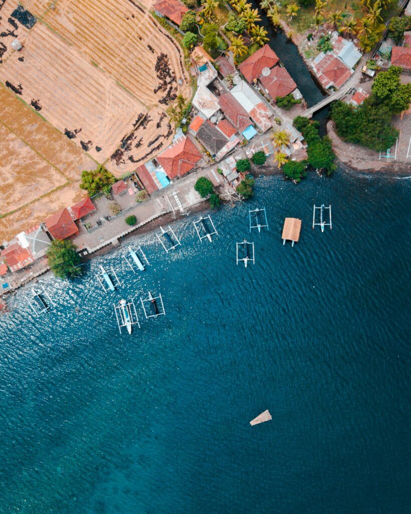 A breathtaking aerial view of Buleleng's coastline in Bali, featuring boats and vibrant blue sea.