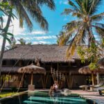Relax by a luxurious pool surrounded by bamboo architecture and palm trees in West Nusa Tenggara.