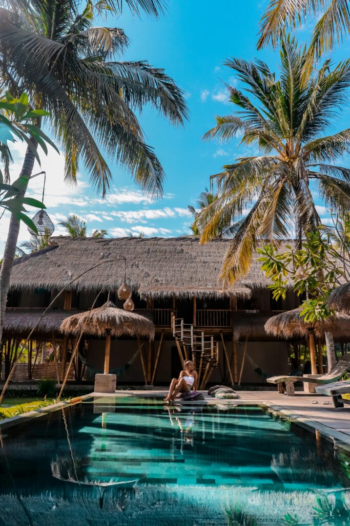 Relax by a luxurious pool surrounded by bamboo architecture and palm trees in West Nusa Tenggara.