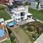 Aerial view of a modern villa with a garden and pool in a suburban area.